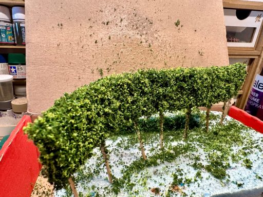 Grüne Bäume in einem Kasten mit verstreutem künstlichem Gras.