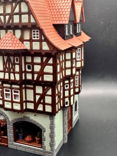 Details eines Fachwerkhauses mit rotem Dach und Fenstern, auf einem dunklen Hintergrund.